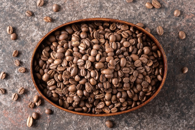 Roasted coffee beans in a wooden box on a dark background.