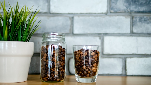 Photo roasted coffee seeds inside a bottle, a glass bottle arrange in line up with little plants