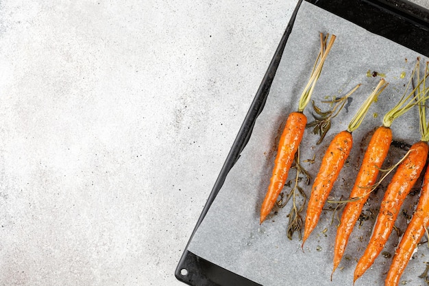 Roasted cooked baked carrots on baking tray top view overhead Healthy vegan food