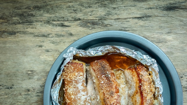 Roasted crispy pork in a dish on wooden table. Cooking home make with microwave.