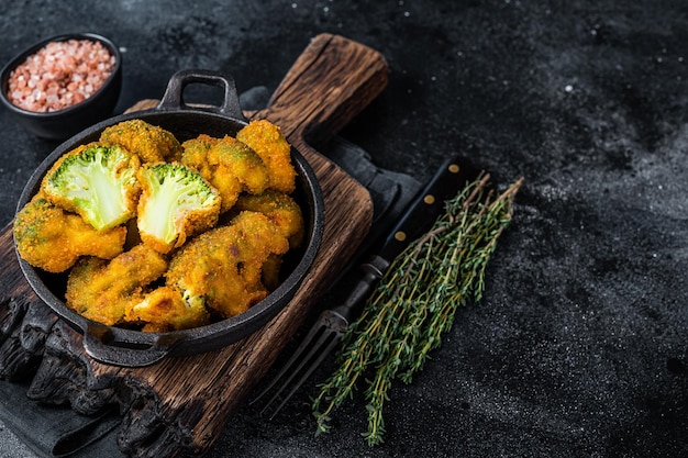 Roasted Crumbed broccoli in a pan. Black background. Top view. Copy space.