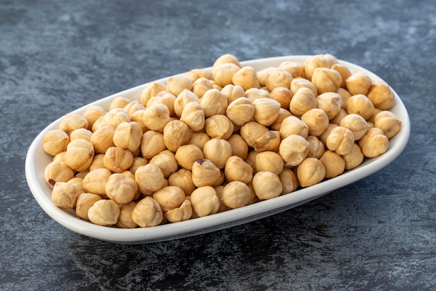 Roasted hazelnuts on plate on dark background