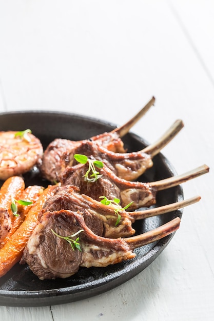 Roasted lamb ribs with vegetables on the white table