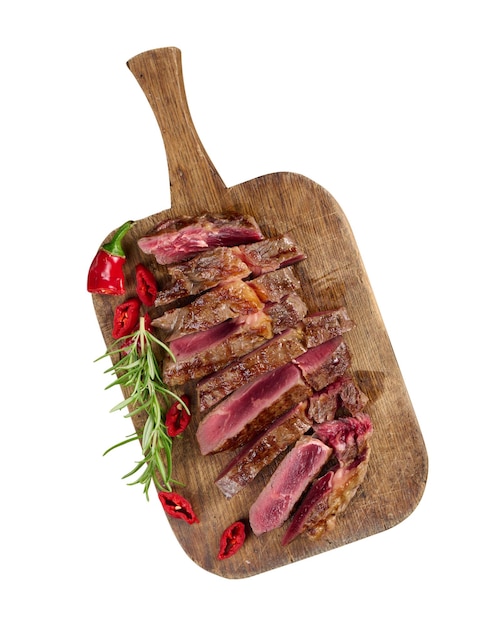 Roasted piece of beef ribeye cut into pieces on a vintage brown chopping board rare doneness Delicious steak food isolated on white background