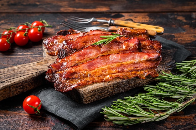 Roasted pork Bacon sizzling slices on wooden board. Wooden background. Top view.