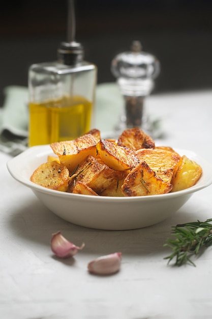 Roasted potatoes in the white plate with garlic, rosemary and olive oil