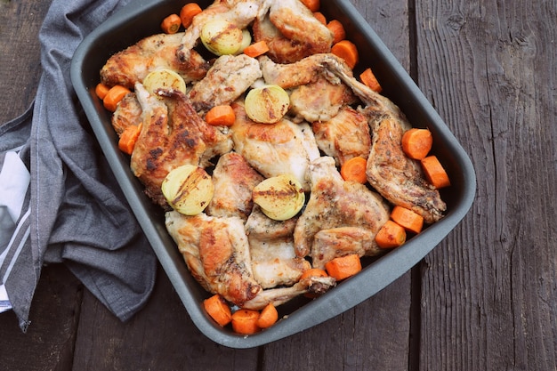 Roasted Rabbit Haunches in Pan with Stewed Vegetables on Rustic Wooden Table Surface