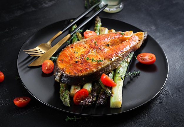 Roasted salmon garnished with asparagus and tomatoes with herbs Ketogenic lunch Keto diet