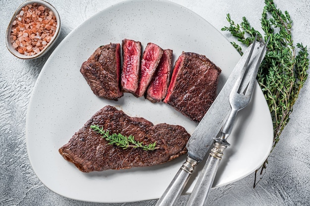 Roasted sliced rump beef meat steak on a plate with thyme.