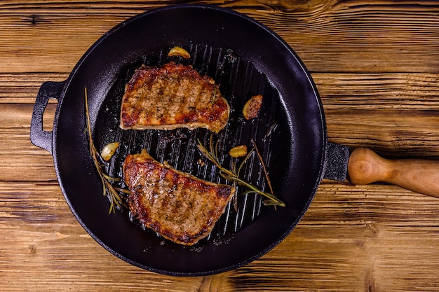 Roasted steaks with garlic rosemary and spices in a cast iron grill pan Top view