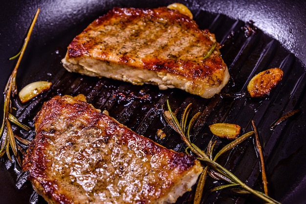 Roasted steaks with garlic rosemary and spices in a cast iron grill pan