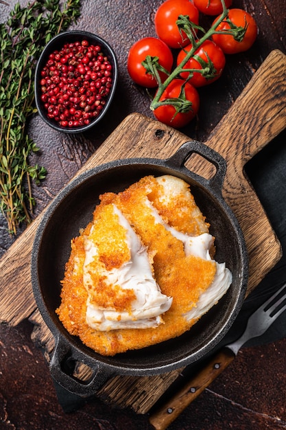 Roasted tilapia fillet in a skillet with breadcrumbs Dark background Top view