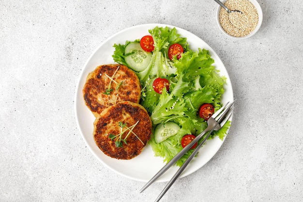 Roasted Vegan Homemade cutlets with Quinoa and vegetable salad on white plate Top view