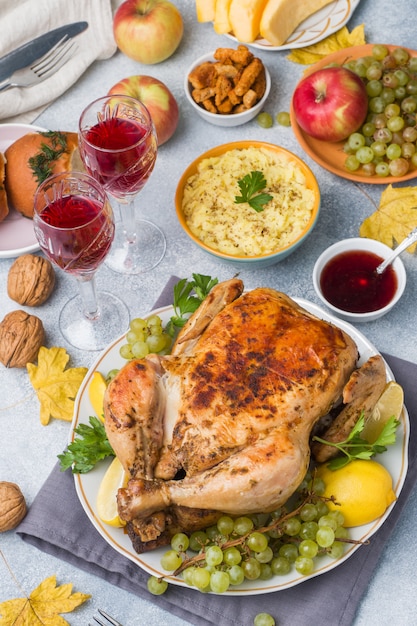 Roasted whole chicken with lemon and grapes on gray light surface