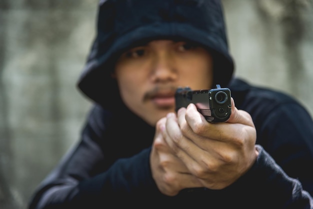 Robber assassin crime with hood points the gun already shoot