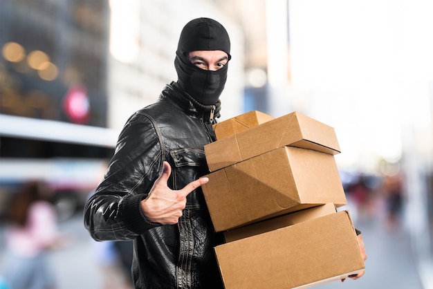 Robber holding boxes on unfocused background