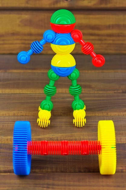 Photo robot sportsman and barbell on a wooden background