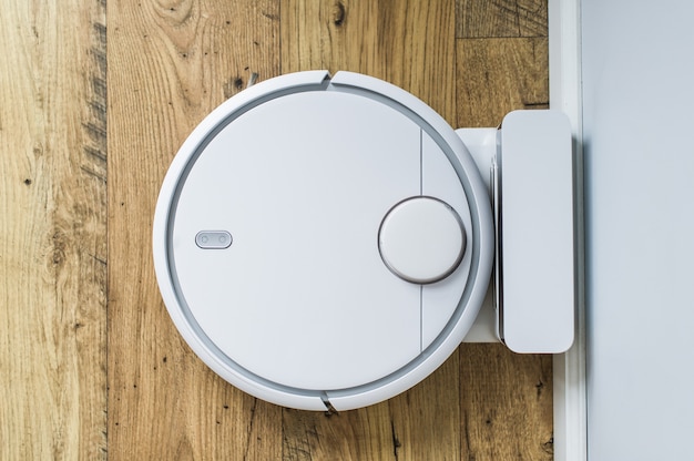 Robot vacuum cleaner on wooden floor. The view from the top. Smart home concept. Automatic cleaning