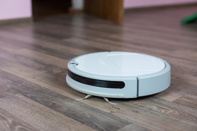 Robotic vacuum cleaner on laminate wood floor smart cleaning technology.