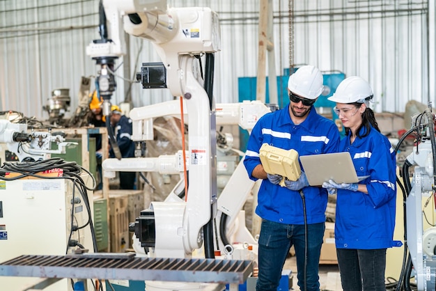 Robotics engineer working on maintenance of modern robotic arm in factory warehouse