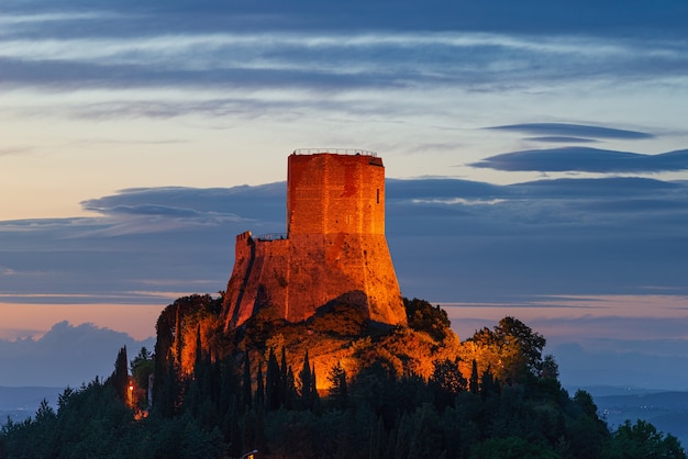 Rocca dOrcia a medieval village and fortress in Orcia Valley Tuscany Italy Unique view at dusk the stone tower perched on rock cliff illuminated against dramatic sky