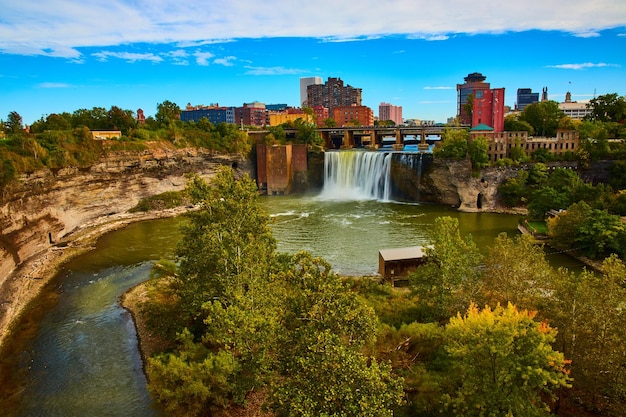 Rochester skyline along river and cliffs with waterfall pouring past bridge