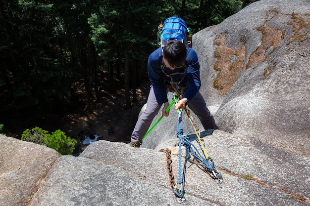 Rock Climber is Rappeling down a steep cliff during a sunny summer day