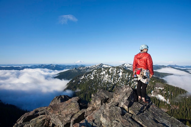 A rock climber stands on the summit of a peak after climbing to the top with the aid of a rope and protection