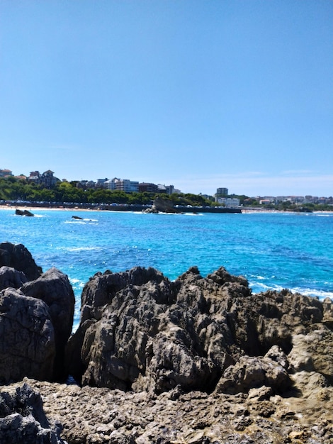 a rock formation is in front of a body of water and a blue sky