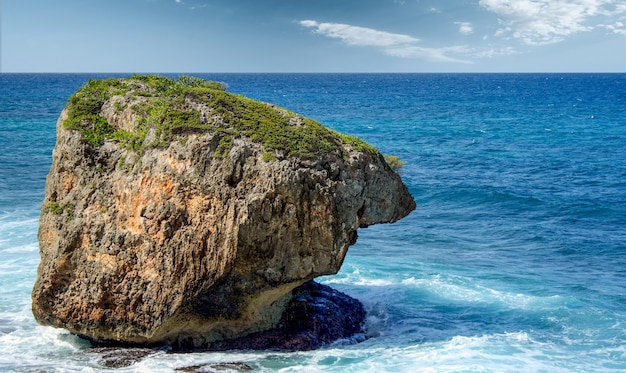 Rock formation rising out of the sea and the water crashing on it