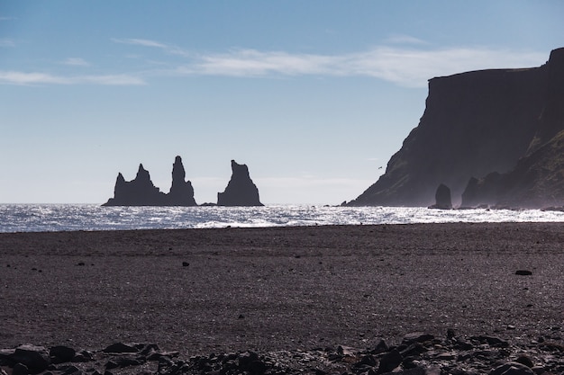 Rock Troll's fingers in the ocean near the beach with black sand in south of Iceland