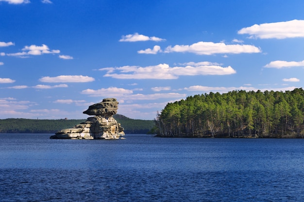 Rock Zhumbaktas on lake. Burnaby National Nature Park in Kazakhstan. Stone figure Sphinx.