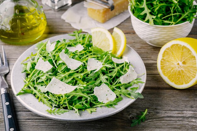 Rocket salad with Parmesan cheese lemon olive oil and seasonings on wooden background