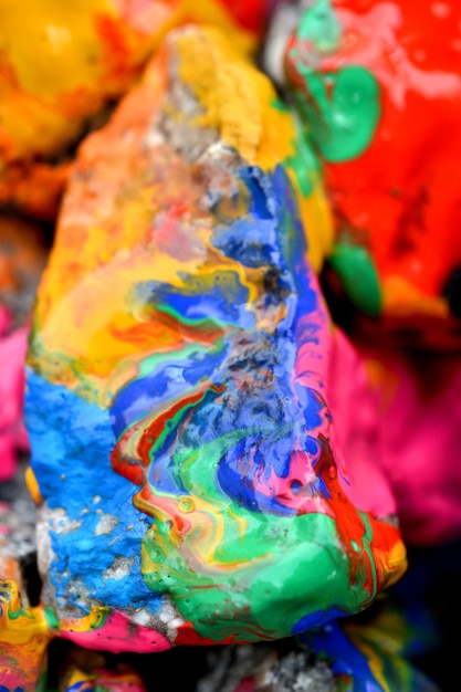 Rocks covered with colorful paint close-up. Stones in the paint with streaks. Abstract background