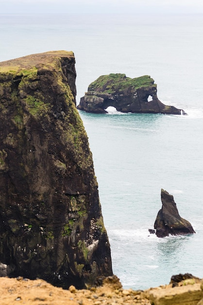 Rocks in ocean and on Dyrholaey cliff in Iceland