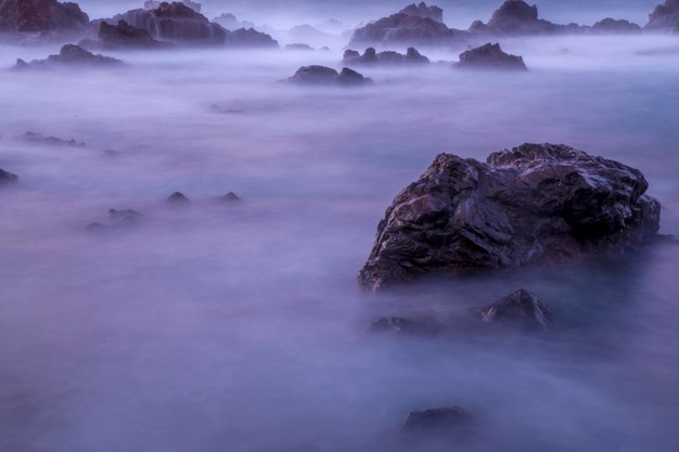 Rocks in the ocean with the sky in the background