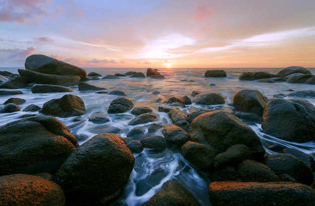 Rocks at sea shore against sky during sunset