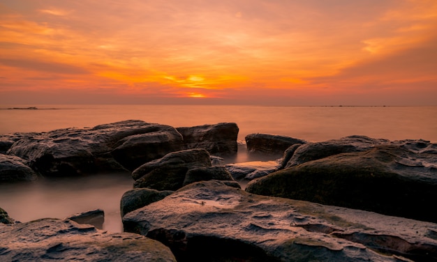 Rocks on stone beach at sunset. Beautiful beach sunset sky. Tropical sea at dusk