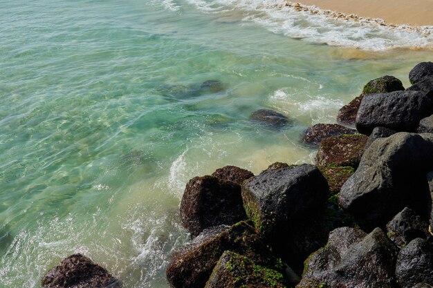 Rocks and waves on a sandy tropical beach