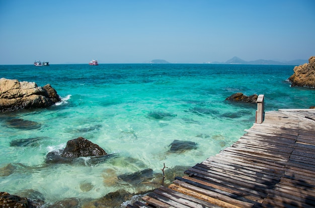 Rocks and wooden bridge on the beach with clear sea water