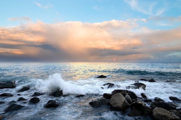 Rocky coast and sea waves at sunset