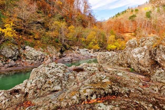 Rocky granite banks of a mountain river and autumn forest