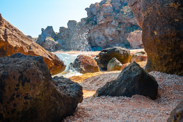 Rocky grotto on the sea coast with splashes of breaking waves on the rocks