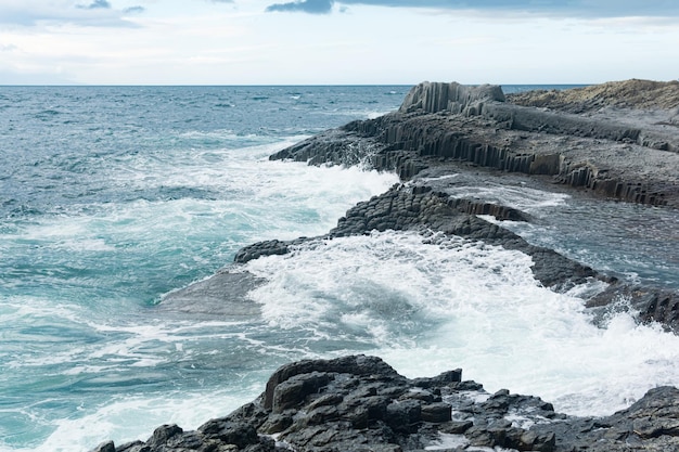 Rocky seashore formed by columnar basalt against the stormy sea coastal landscape of the Kuril Islands