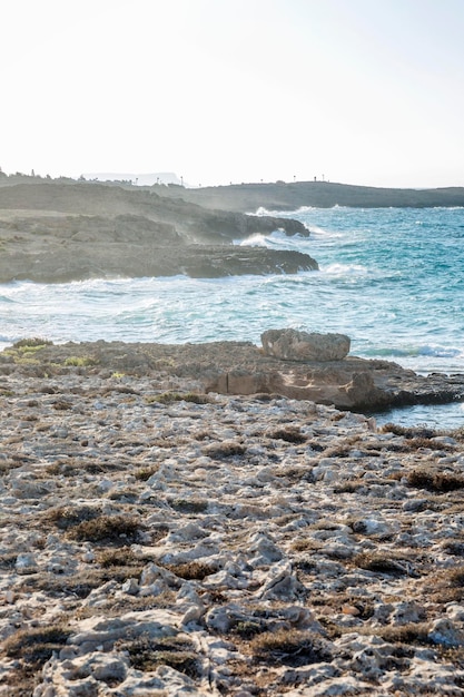 Rocky shore of the turquoise sea against a clear blue sky at dawn Beautiful scenery and relaxation Vertical