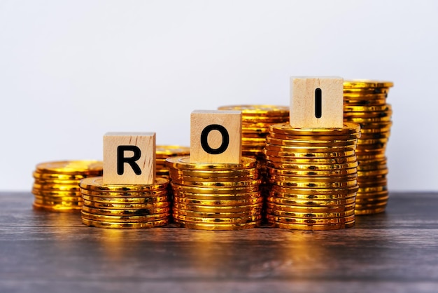 ROI Return of Investment Text on Wood Block With Stack Of Coins