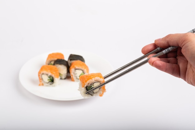 Roll of sushi on a plate, Sushi roll on a tablet, white background, Sushi roll and hand with chopsticks