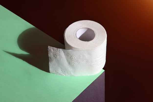 Roll of toilet paper on edge concept for sale and necessity on dark background