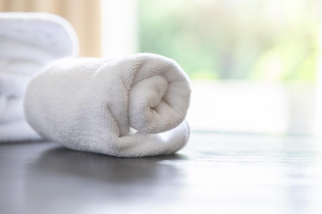 Roll up of white towels on table with copy space on blurred room background