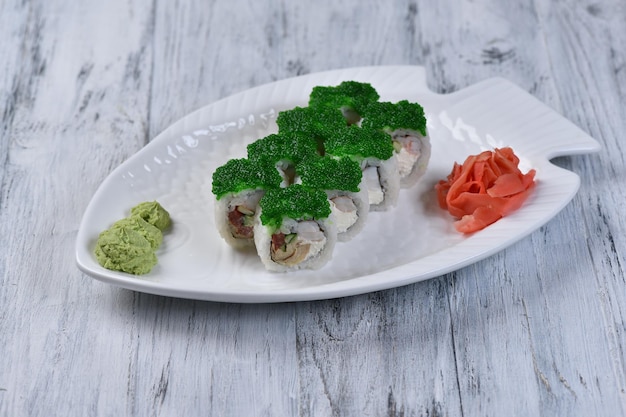 Roll with green tobiko with wasabi and ginger. A dish of Japanese cuisine on a gray table.Top view